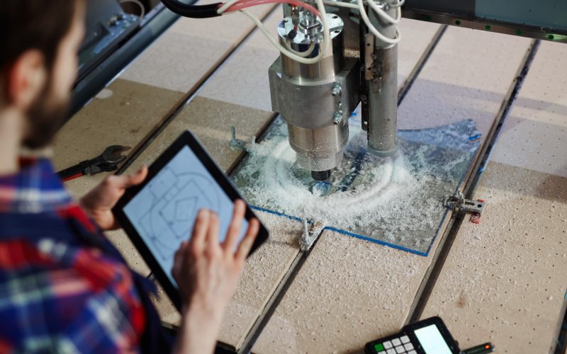 Engineer with touchpad and lathe machine